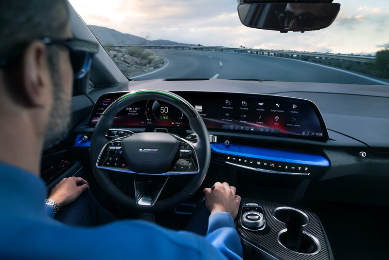 Front View of the 2026 OPTIQ-V Driving Through the Dusk Utilizing its Headlights | Powell Watson Cadillac of Laredo in Laredo TX