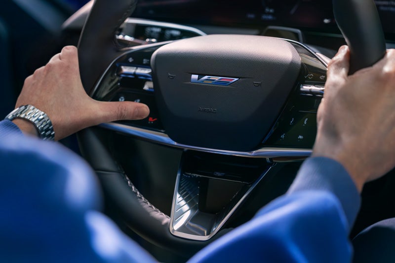 Close-up of a Man About to Press the V-Button on the 2026 OPTIQ-V Steering Wheel | Powell Watson Cadillac of Laredo in Laredo TX
