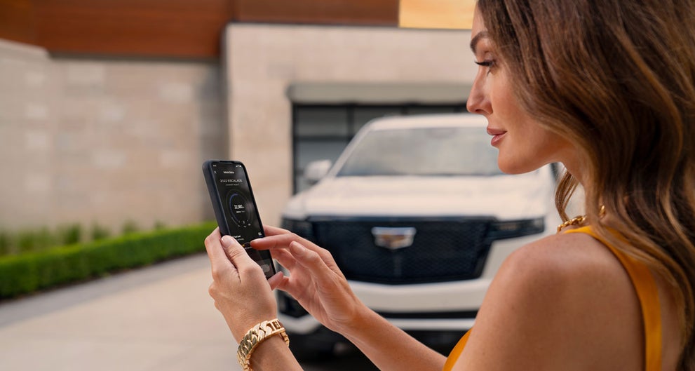 lady checking her mobile with a Cadillac vehicle background | Powell Watson Cadillac of Laredo in Laredo TX